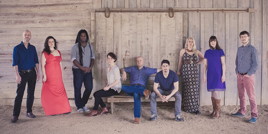 Posed photo of vocal group Roomful of Teeth in front of barn doors. Photo by Bonica Ayala.